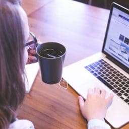 woman with a tea cup using a laptop