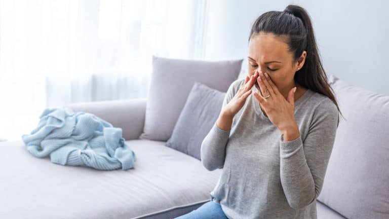 Woman with sinus pressure holding hands to her face.