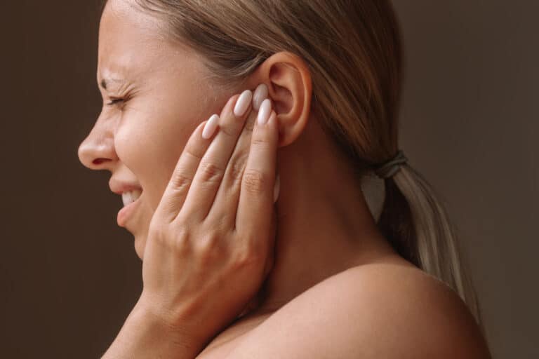 Woman with tinnitus holds ear