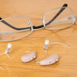 Hearing aids sitting next to glasses