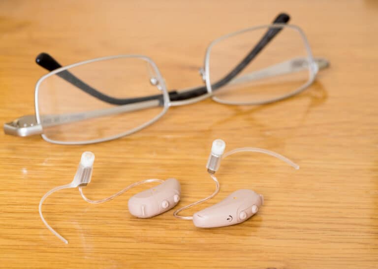 Hearing aids sitting next to glasses